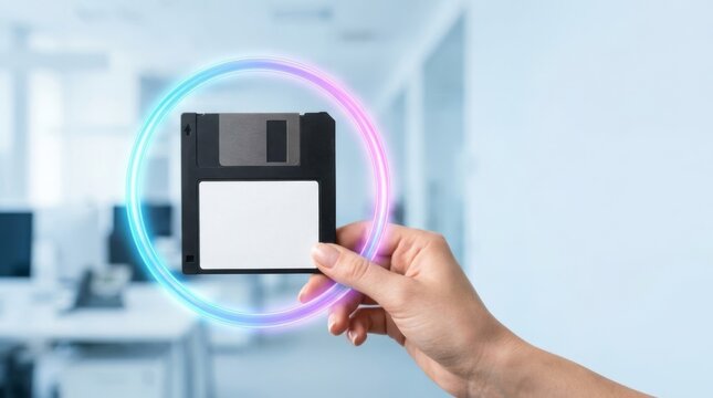 Hand holding floppy disk with neon ring in modern office, data protection concept