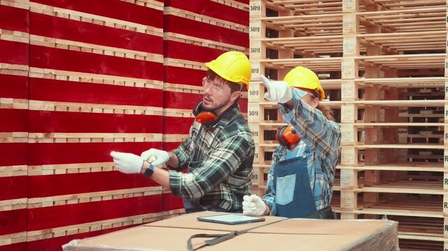 Workers measure wood in a warehouse