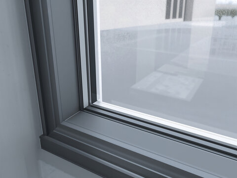 Dark grey window frame corner showing the clean lines and structure of a glass pane with a blurred outdoor view in the background setting