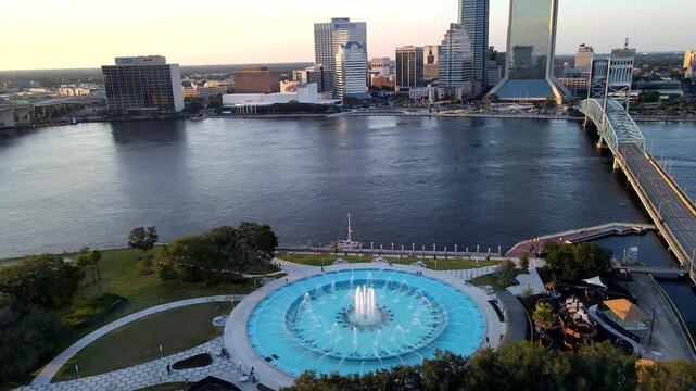 Moving aerial view reveals tall central water jet around Friendship Fountain in Florida.
