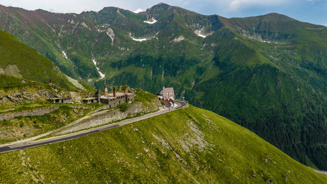 Aerial view of the Transfagarasan mountain pass winding through the Carpathian Mountains with historic stone structures and lush green slopes in Curtea de Arges, Judetul Arges, Romania.