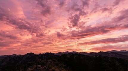 Fototapeta premium Vibrant pink and orange sunset sky over a dark mountainous horizon