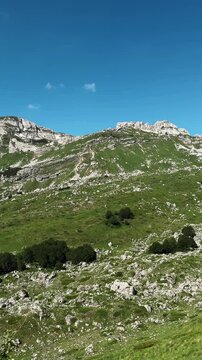 Small alpine lake lies among rocky green slopes at Sedlo Pass in Durmitor Montenegro. Summer scenery for hiking tourism adventure and ecotourism