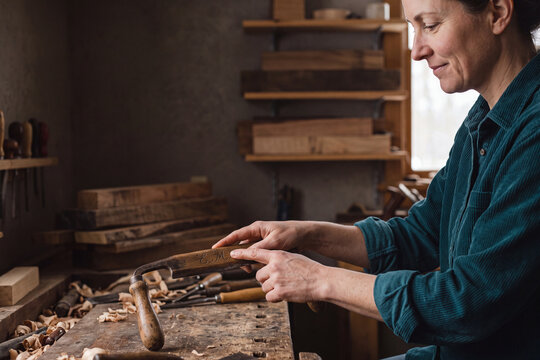 Craftswoman tracing carved initials on a vintage woodworking tool