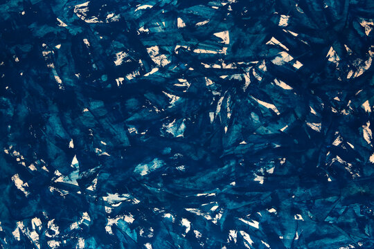 Deep blue tones swirl in abstract, textured patterns. White highlights break through the rich navy, adding contrast and depth. Mottled surface evokes natural, organic movement