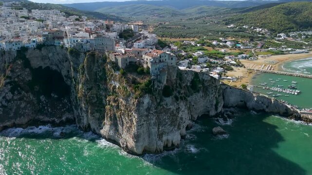 Peschici Gargano Puglia Italy 4K drone video. Perched cliff castle hanging over sea with vertical drop and distant beach marina. Scenic travel b roll stock footage