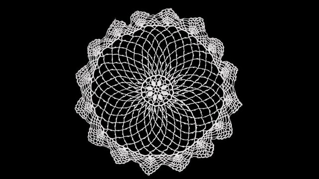 Round crochet white napkin lace isolated on black background, crocheted Grandma's doily lace, detail of handmade embroidery, tablecloth, napkin, vintage art design. Flat lay, top view, rotating