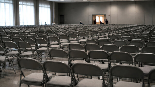 Rows of empty chairs arranged in a large conference hall before a business event, seminar or public presentation