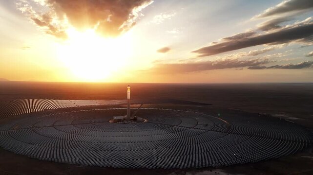 tower solar thermal power plant with heliostat mirrors and central receiver tower at sunset