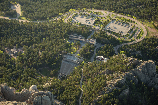 Aerial view of Mount Rushmore National Memorial amphitheater and visitor center surrounded by dense pine forests in Keystone, South Dakota, United States.