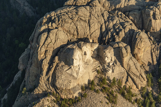 Aerial view of Mount Rushmore National Memorial featuring the carved faces of US presidents on granite rock, surrounded by pine forests in Keystone, South Dakota, United States.