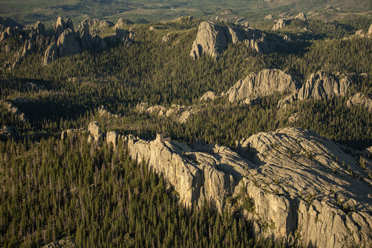 Aerial view of a fire lookout tower perched on a rocky ridge surrounded by dense pine forests in the Black Hills near Keystone, South Dakota, United States.