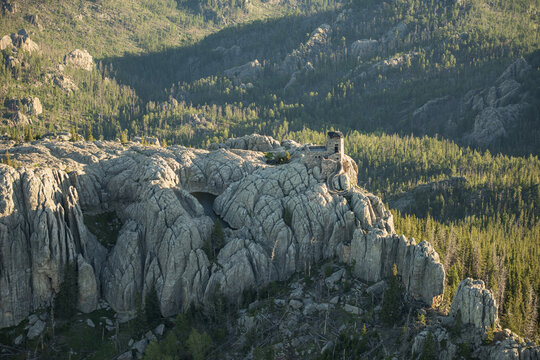 Aerial view of the Needles rock formations and a historic stone lookout tower surrounded by dense pine forests in Custer State Park, Keystone, South Dakota, United States.