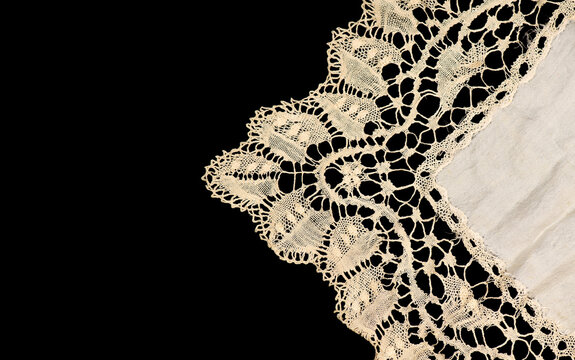 Antique bobbin lace doily border, square bobbin needle lace napkin isolated on black background, beige silk bobbin lace with gimp trim, vintage textile design, antique fabric art. Top view