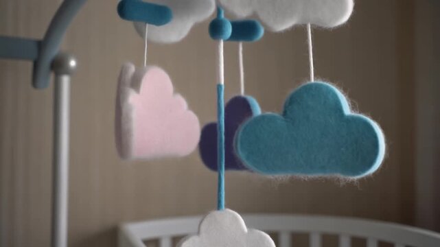 Felt cloud mobile turning above a cot