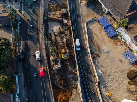 Aerial view of road construction site with excavators working on a busy street in Yogyakarta, Special Region of Yog, Indonesia.