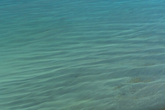 Aerial view of turquoise ocean water with gentle ripple patterns and visible sandy seabed in the Shire of Shark Bay, Western Australia, Australia.