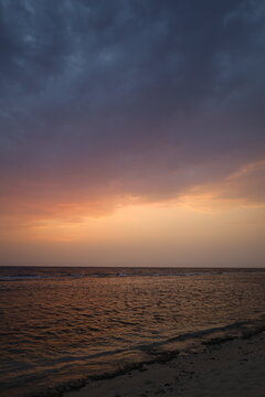 Panoramic view of calm sea horizon under dramatic sunset sky with orange and cloudy gradient, ideal for travel, wellness, and background design