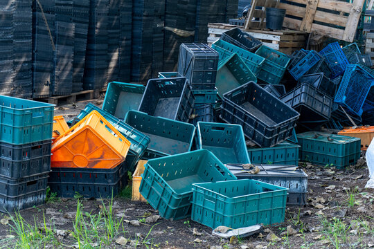Heap of colorful plastic harvest crates piled outdoors on farm ground