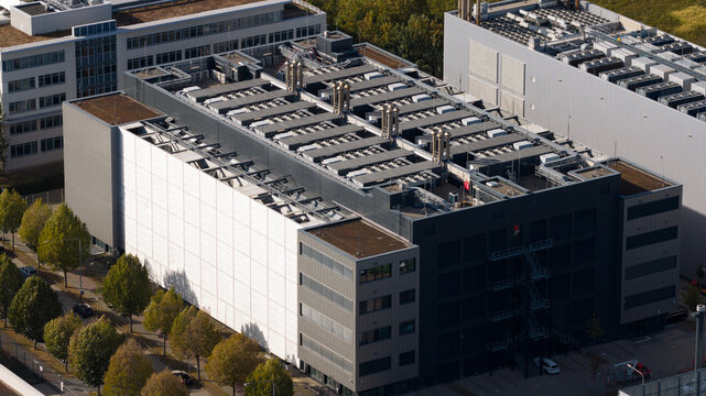 Aerial view of the Sossenheim datacenters featuring modern industrial architecture with large rooftop HVAC units and a prominent white facade section in Frankfurt am Main, Hessen, Germany.