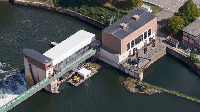 Aerial view of the Neckar-Staustufe und Schleuse Rockenau, featuring the lock and weir infrastructure on the Neckar river, with a maintenance barge in Eberbach, Baden-Wurttemberg, Germany.