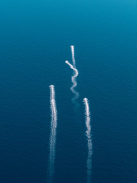 Aerial view of three boat wakes creating white trails on the deep blue Mediterranean Sea near Le Trayas, Saint-Raphael, Provence-Alpes-Cote d'Azur, France.