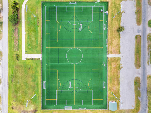 Aerial view of nCino Sports Park featuring a green synthetic turf soccer field with white and yellow markings surrounded by grass and parking areas in Wilmington, North Carolina, United States.