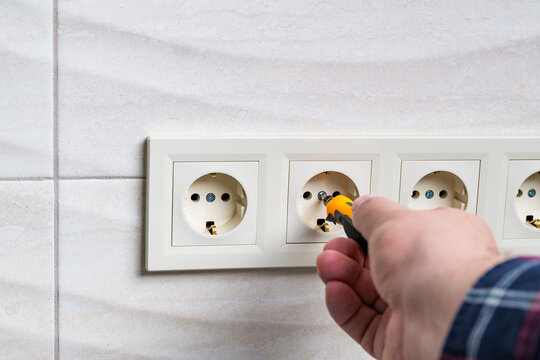 Screwdriver installing electric socket on marble wall