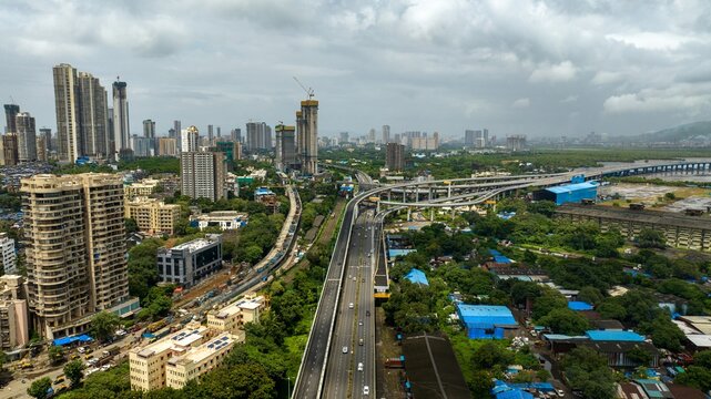 Aerial view of the Atal Bihari Vajpayee Sewri Nhava Sheva Atal Setu bridge spanning across the landscape with urban high-rise buildings and lush greenery in Mumbai, Maharashtra, India.