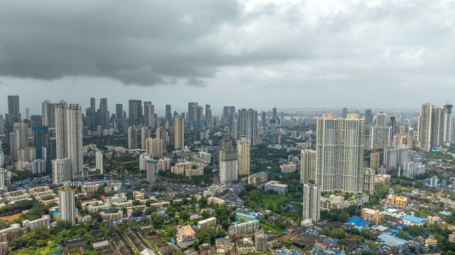 Aerial view of the dense urban skyline of Mumbai with high-rise residential towers, sprawling neighborhoods, and a cloudy sky over the city in Mumbai, Maharashtra, India.