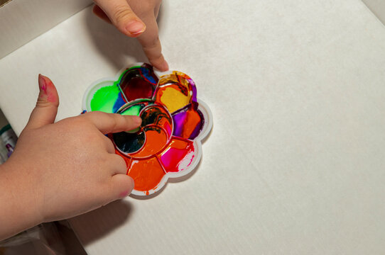 Child Finger Painting with Colorful Palette and Copy Space.