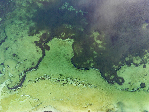 Aerial view of Attensee showing clear turquoise and deep green water patterns with sandy lakebed textures in Rottenbach, Bayern, Germany.