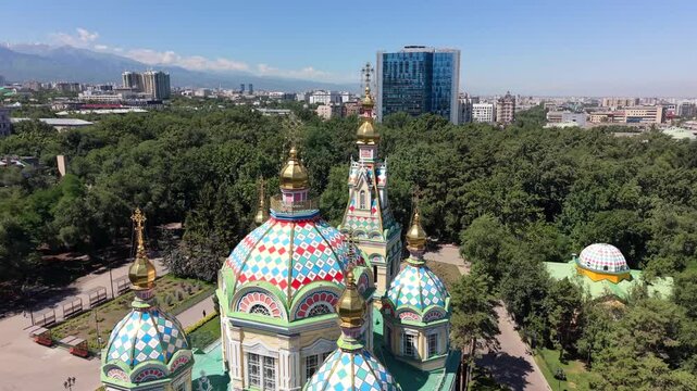 Aerial view of the colorful domes of the historic Ascension Cathedral surrounded by lush park trees in Almaty, Almaty Region, Kazakhstan.