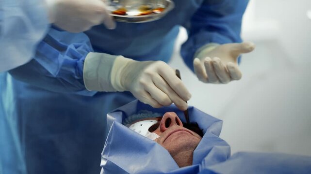 Ophthalmologist performing a surgical procedure on a patient eye under sterile surgical draping