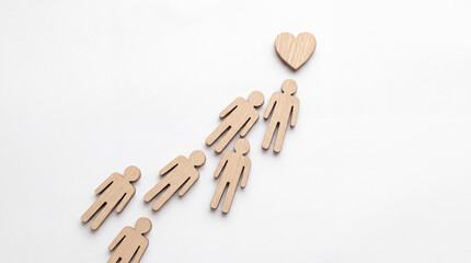 Obraz premium Minimalist Concept of People Moving Toward Love or Compassion Symbolized by Wooden Human Figurines and a Heart Shape on a White Background for Charity, Unity, and Social Support Theme.