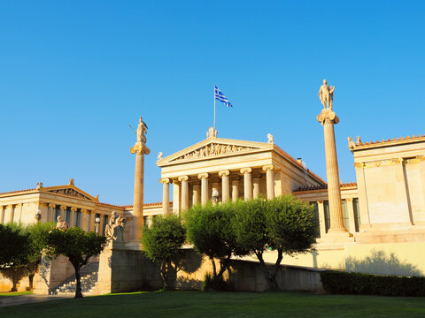 The Academy of Athens with classical columns and statues under blue sky in Athens, Greece