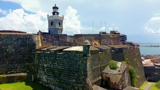 Semi circular drone shot of el Morro Castle and it's lighthouse with some visible tourist visible in the interior of the castle. 