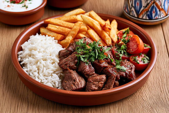 Juicy beef, rice and fries in dish on the table