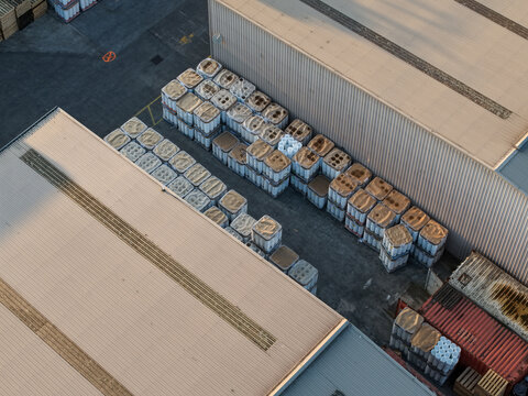 Aerial view of industrial site with rows of white storage containers stacked near factory buildings and a shipping container in Melbourne, VIC, Australia.