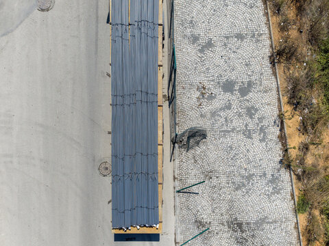 Aerial view of a truck loaded with steel bars on a wooden pallet parked on an asphalt road next to a cobblestone path in Istanbul, Istanbul, Turkey.