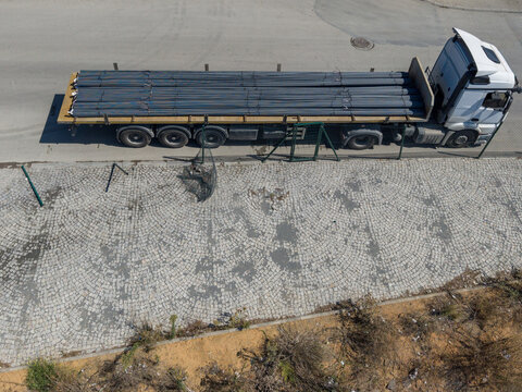 Aerial view of a flatbed truck loaded with long metal pipes parked on a cobblestone surface in Istanbul, Istanbul, Turkiye.
