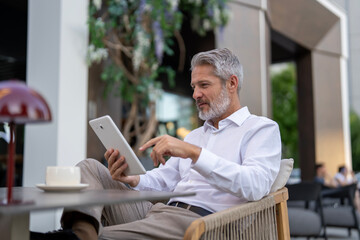 Mature man engaging with digital tablet outdoors © Jelena