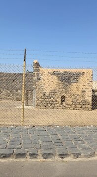 Tracking shot of fenced ancient stone ruins at a historical heritage site in Medina.