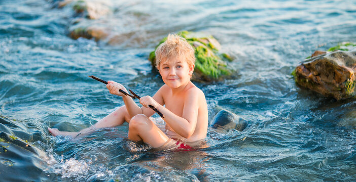 5 year old blond boy making a playful face in warm seaside light.