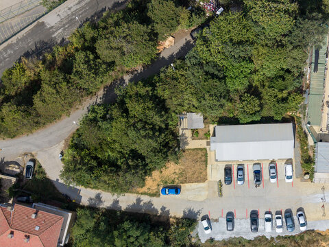 Aerial view of a parking lot with several cars parked near a building surrounded by dense green trees and vegetation in Istanbul, Istanbul, Turkiye.