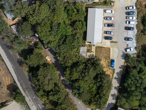 Aerial view of a parking lot with several cars parked in rows next to a modern building surrounded by dense green trees and a paved road in Istanbul, Istanbul, Turkey.