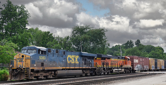 A CSX Transportation locomotive leads an easstbound freight train on Burlington Northern Santa Fe tracks through a Chicago suburb.