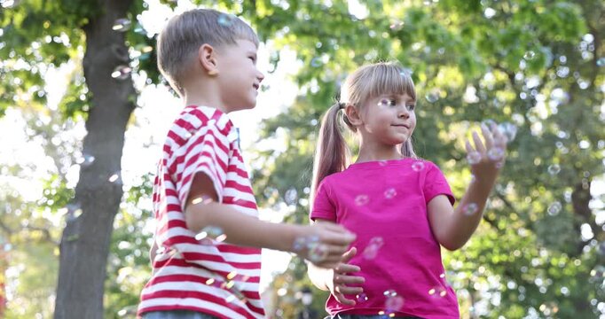Cute little kids having fun with soap bubbles outdoors, low angle view