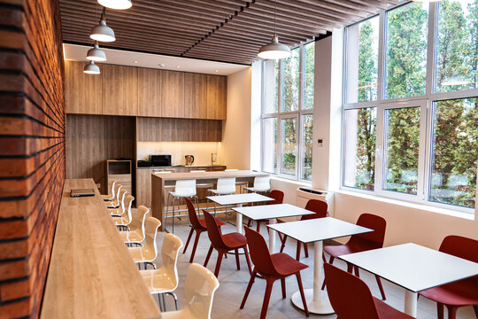 Empty bright office cafeteria or canteen with kitchen area and large windows