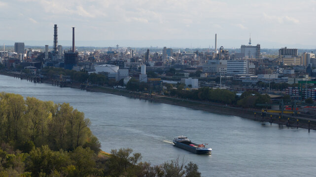Aerial view of the BASF chemical plant complex along the Rhine river with a cargo ship navigating the waterway in Ludwigshafen am Rhein, Rheinland-Pfalz, Germany.
